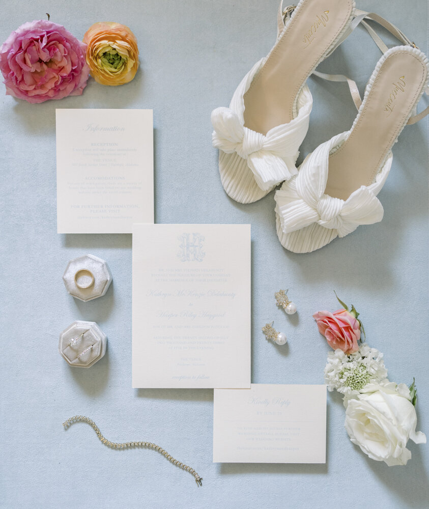 flat lay of wedding stationery with flowers, bridal shoes, and other items