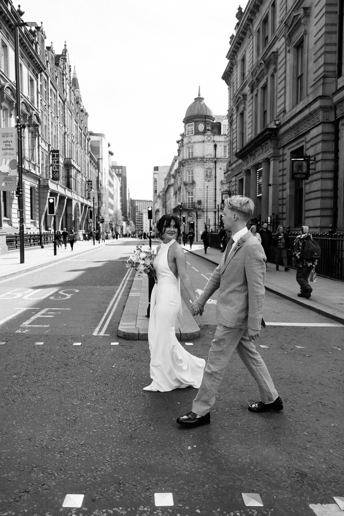 Bride and groom walking through Leeds city centre in black and white