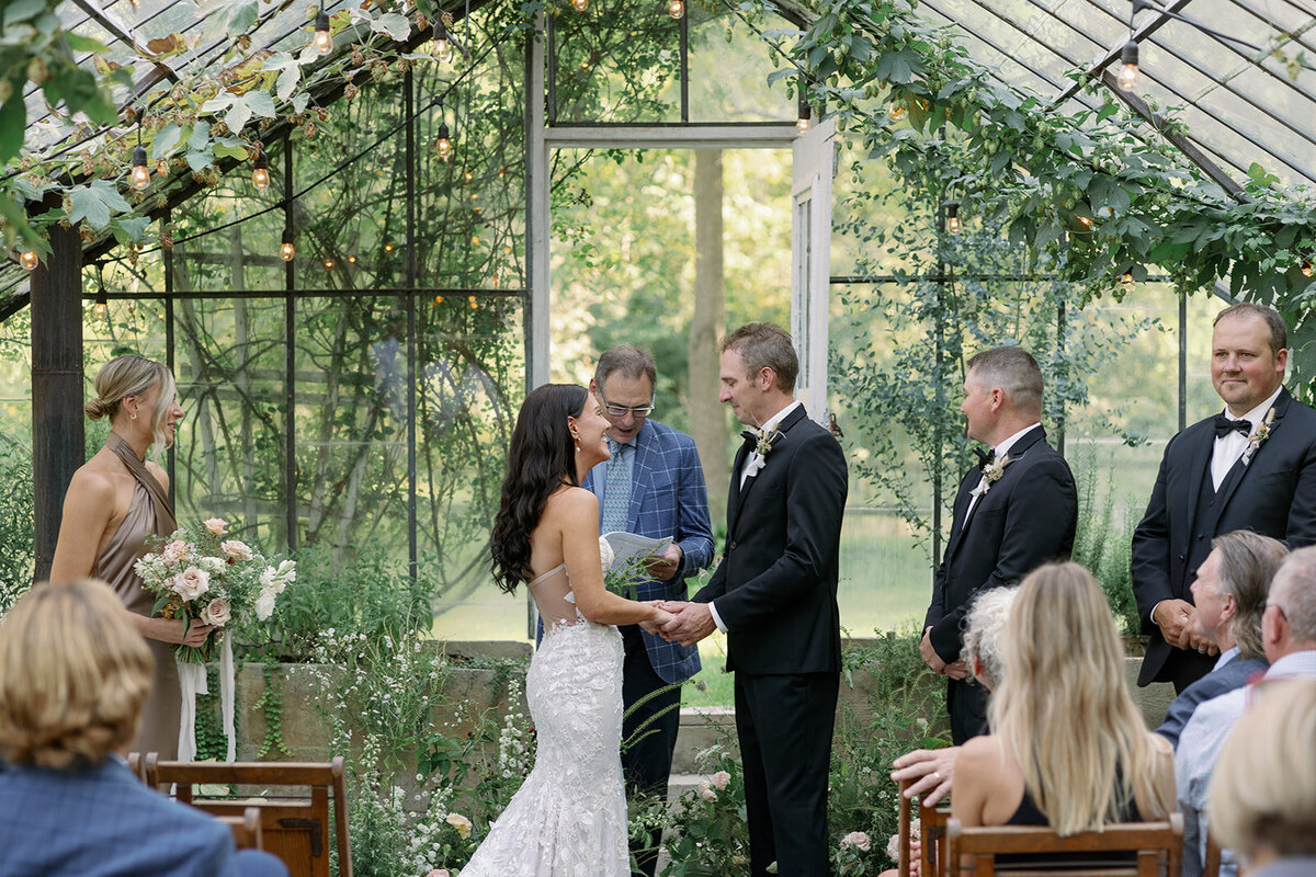 Bride and groom share their first kiss inside the glass greenhouse at Glasshouse Community during their intimate Michigan ceremony.