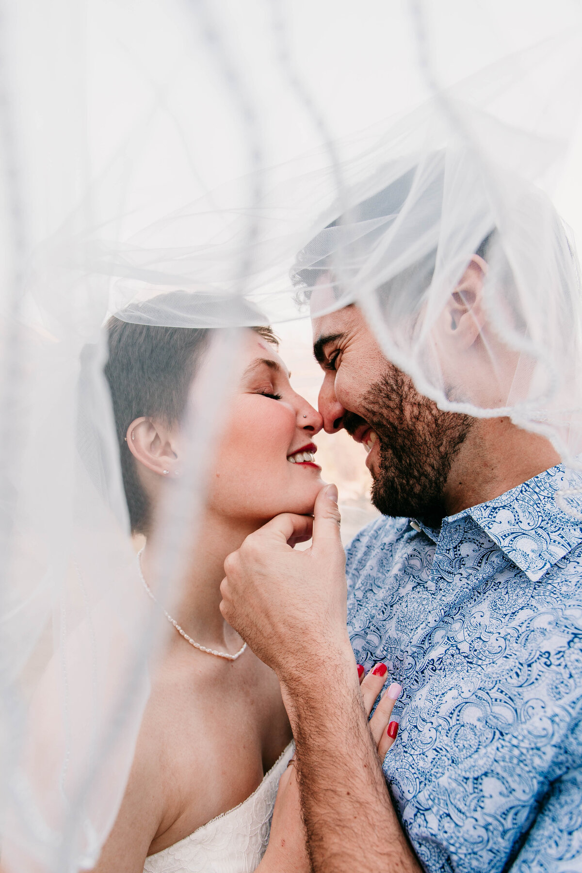 couple kisses under wedding veil