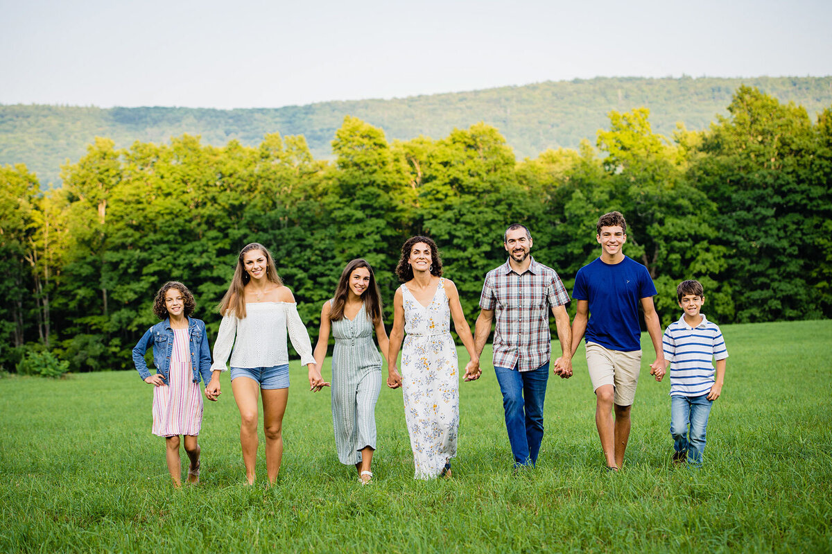 vermont family holding hands walking through field