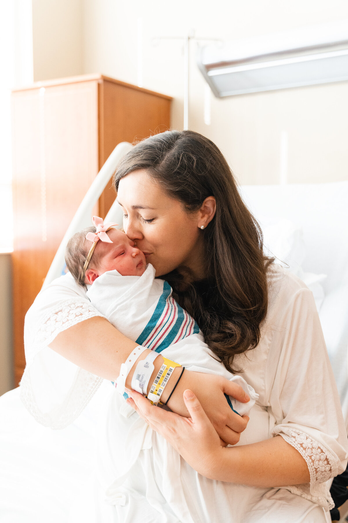 Chattanooga newborn photographer Kelley Hoagland Fresh 48 session with newborn girl at Erlanger East Hospital.  Mother swaddling infant with kiss pose.