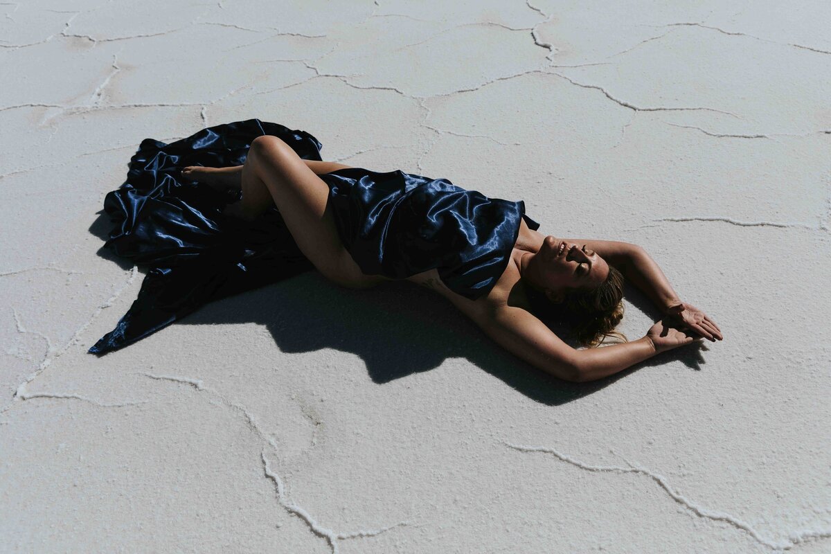 Woman laying on the bonneville salt flats with a satin sheet