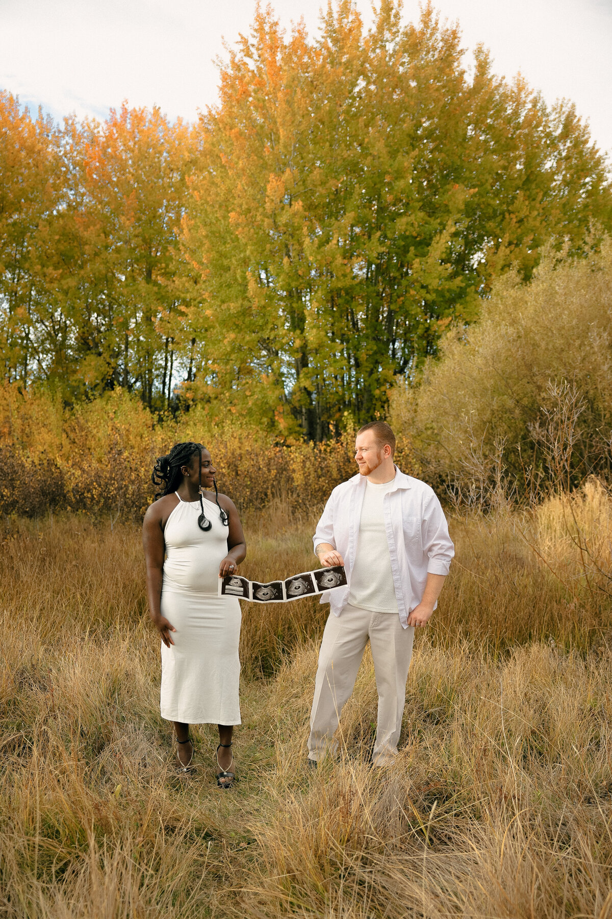 Joyful Pregnancy Announcement Holding Ultrasound in Autumn Meadow