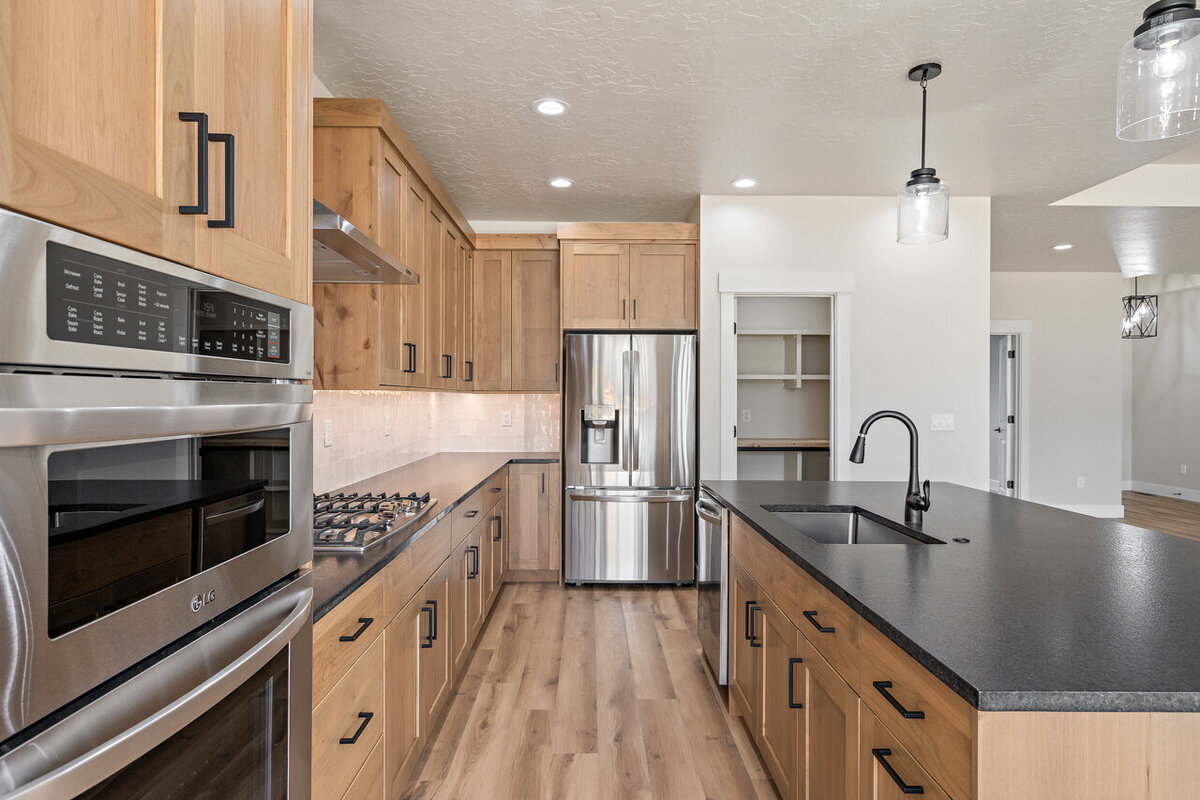 modern kitchen with black counter tops wood cabinets and stainless steel appliances