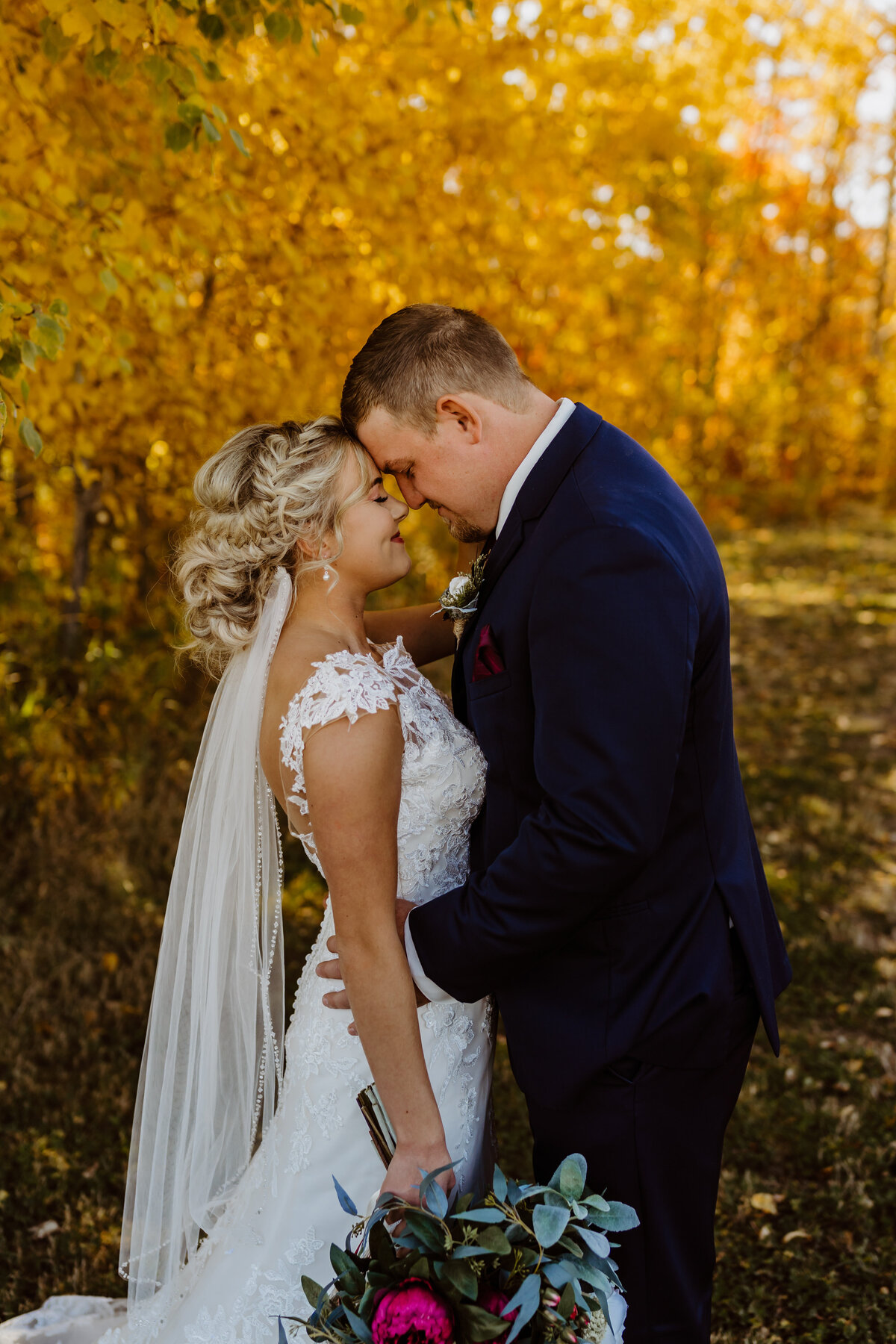 autumn wedding couple eyes closed holding each other with flowers