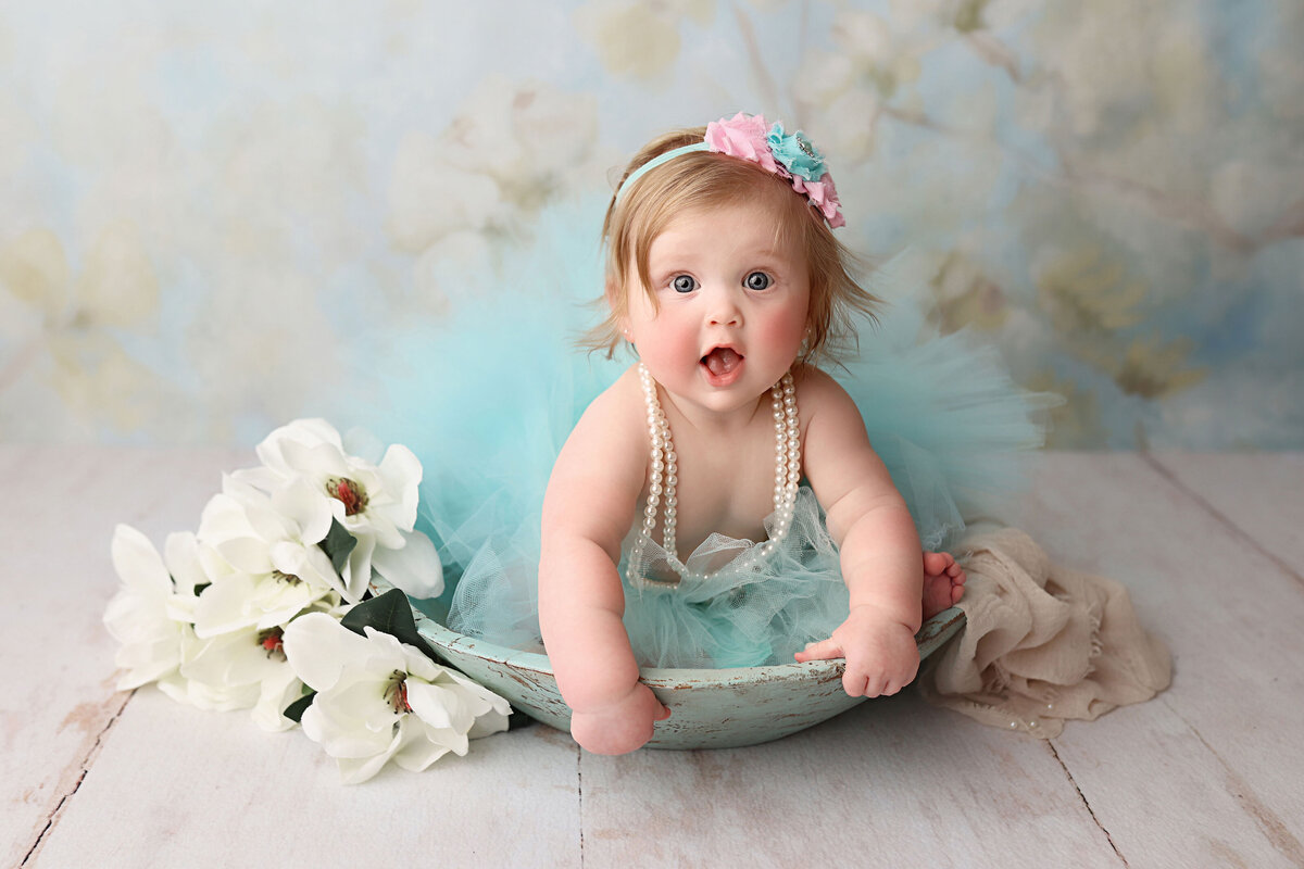 sweet baby girl wearing a blue tutu and  pearl necklace during her birthday session