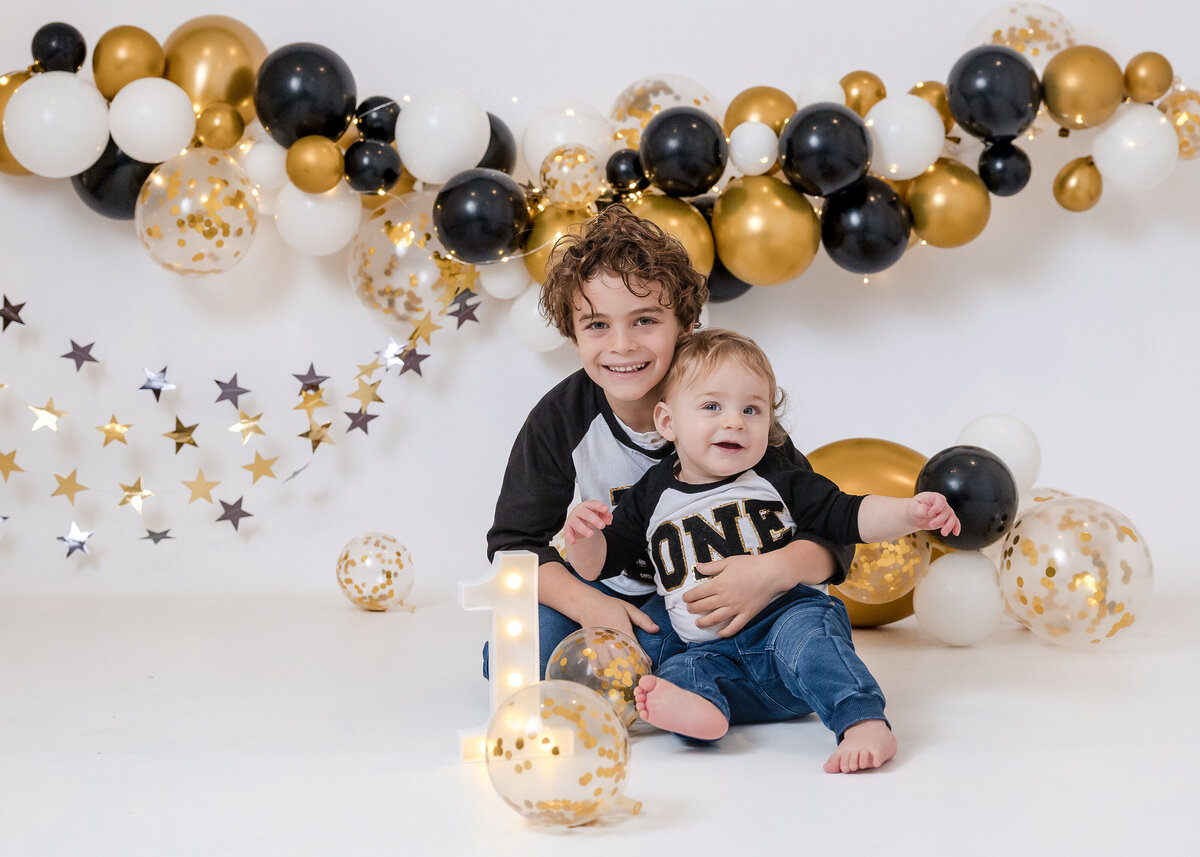 Light and airy photo of 1 year old baby and big brother hugging at Allison Reilly's Union County, NJ photo studio.