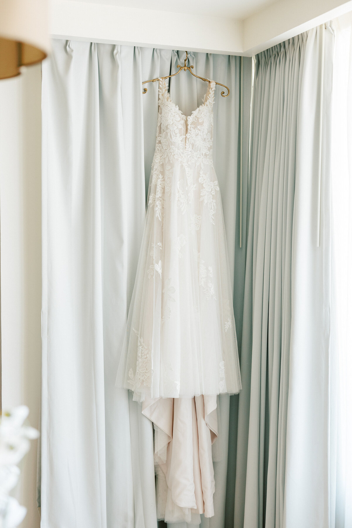 Bridal gown hanging in soft natural light in Cancun, ready for portraits by a Philadelphia wedding photographer.