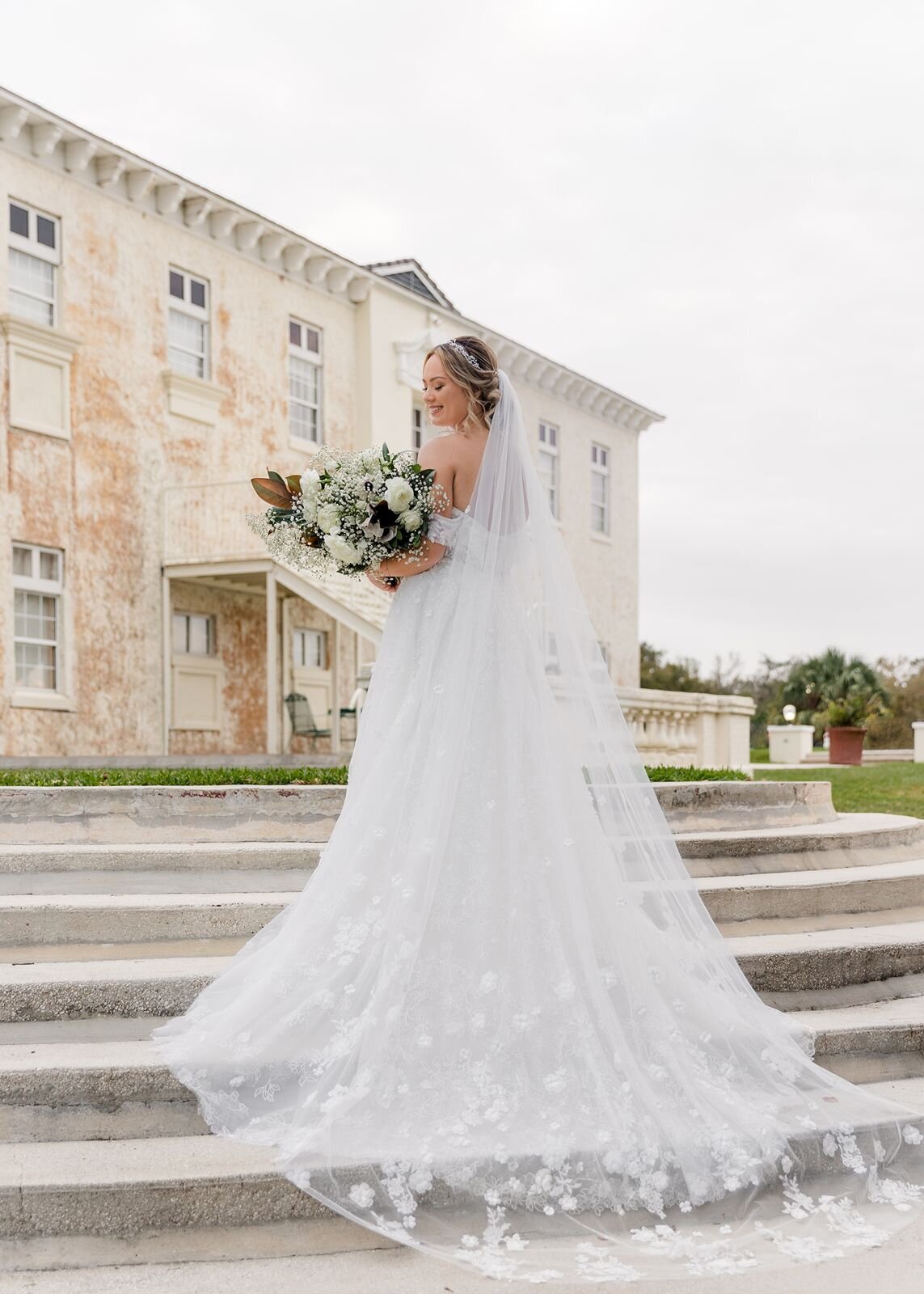 Bride with veil and florals on stairs at Bella Cosa, Lake Wales, Florida