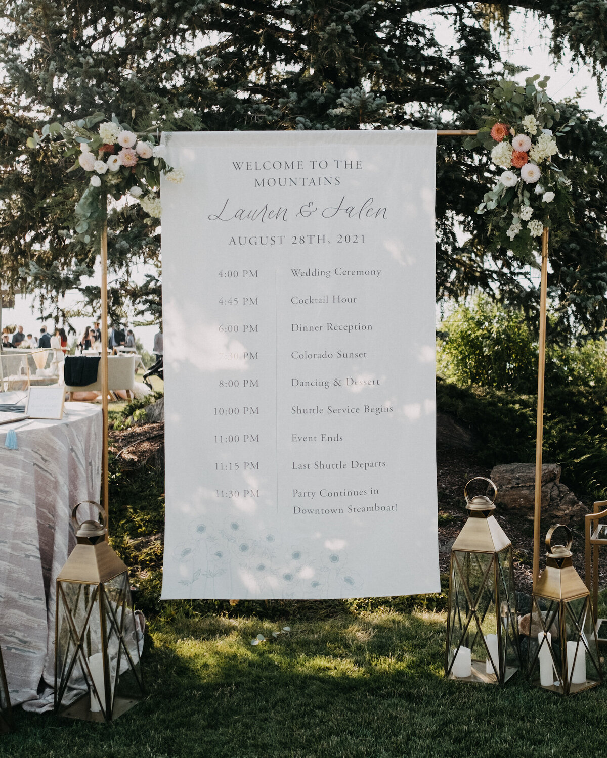 Long fabric wedding welcome sign and program hung on a gold stand with dusty blue anemone flower illustrations