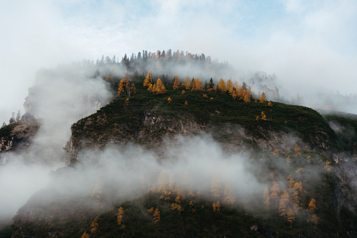Clouds rolling over mountain ridge with autumn trees