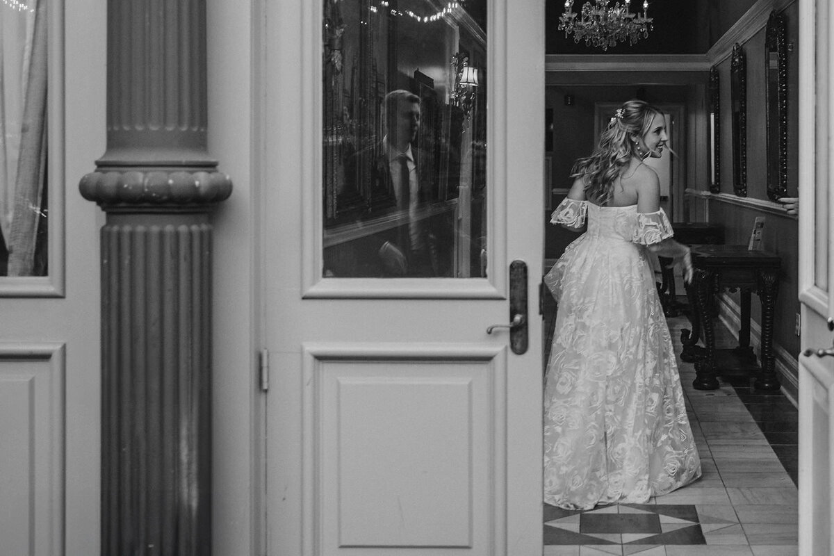 A person in a wedding dress standing just inside of a door