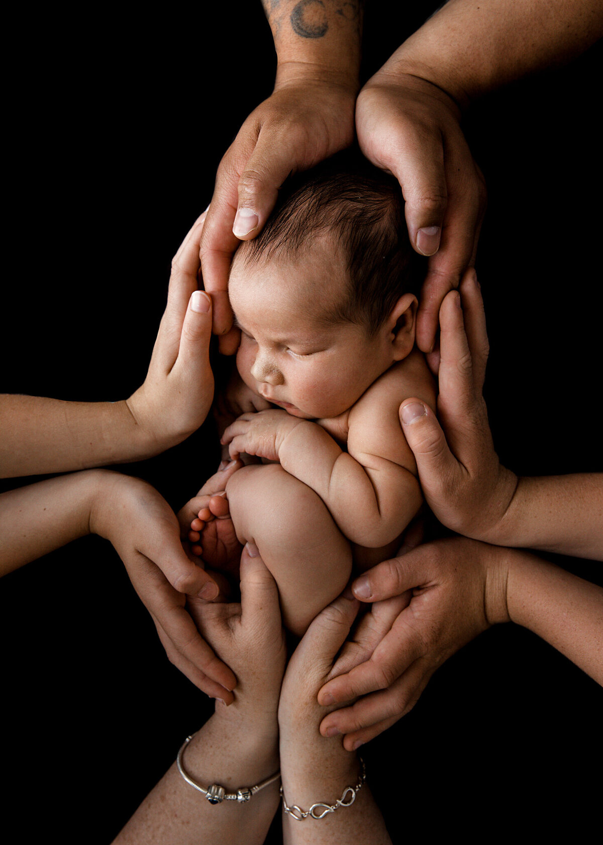baby with family all covering him with their hands