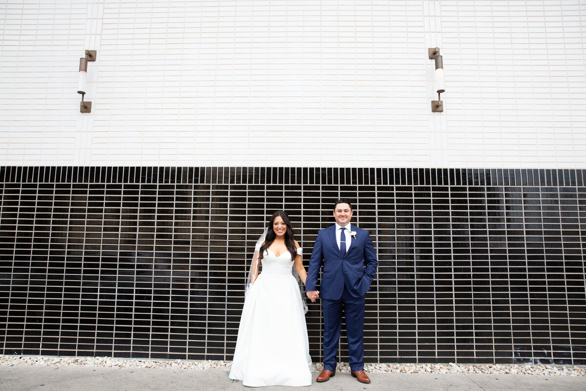 An Austin wedding photographer capturing a bride and groom in front of a brick wall.