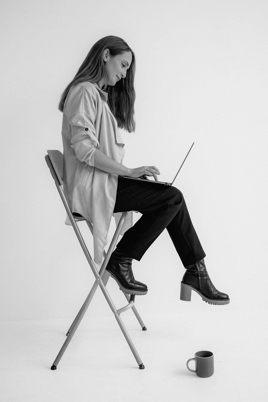 Woman sitting on a high chair while typing on her laptop.