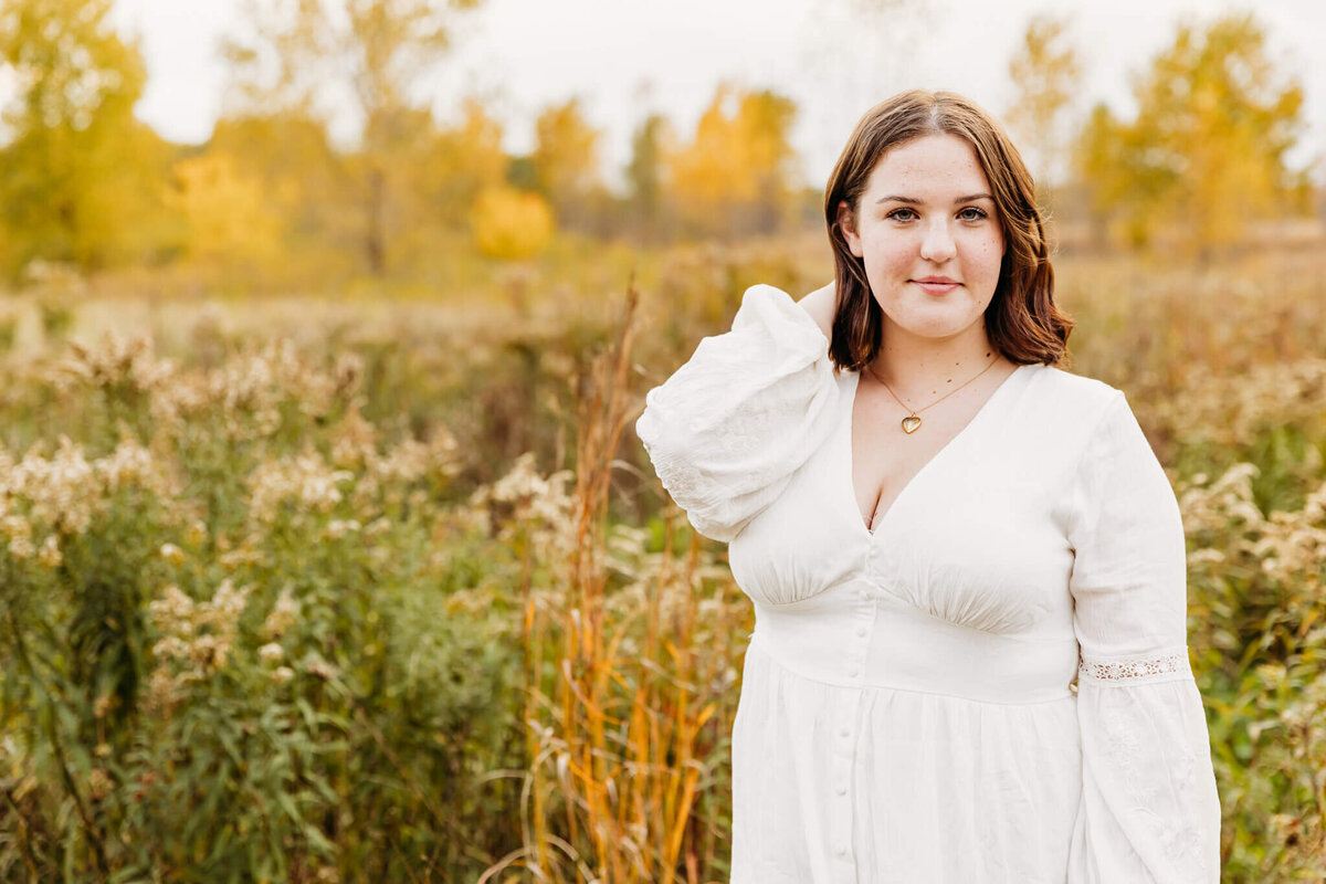 girl with short hair in a white long sleeve dress laughing during her senior session