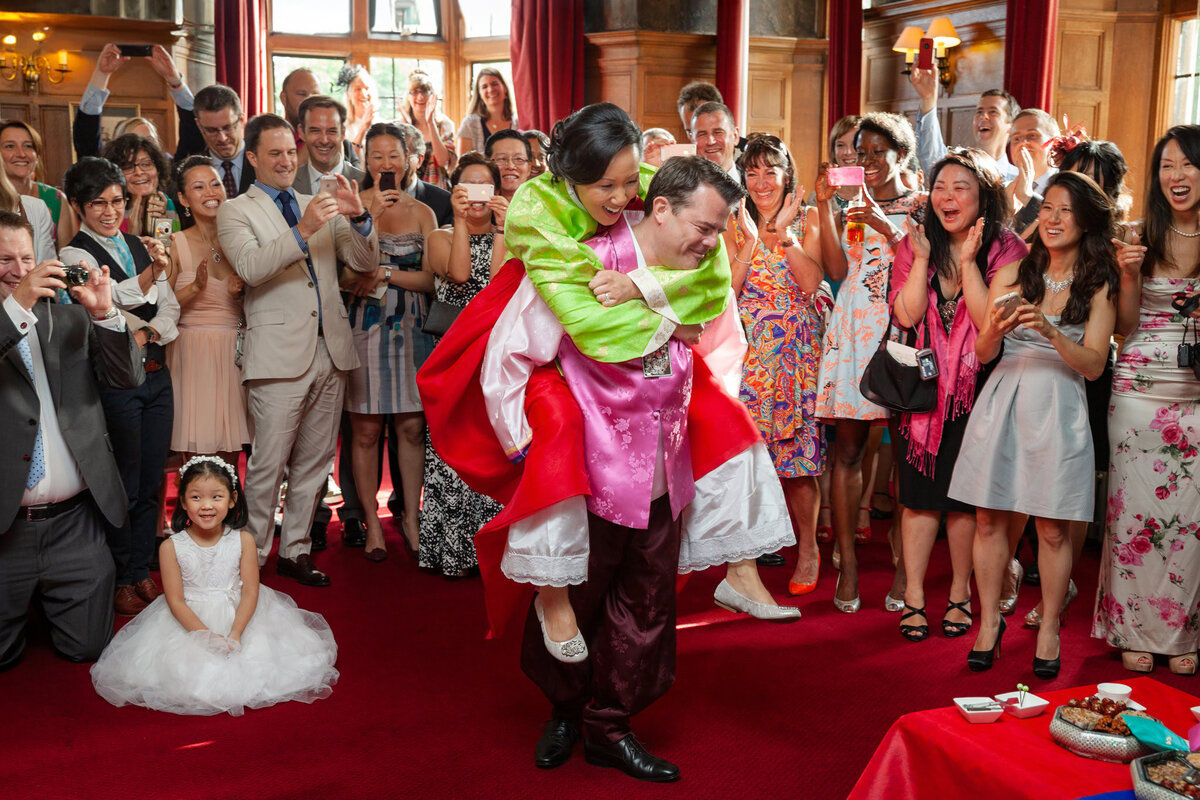 Groom giving bride a traditional Korean 'piggyback' at the end of their ceremony to show his support for her