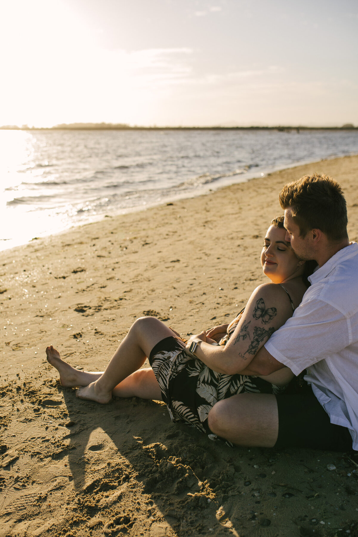 A Bendigo Wedding photographer captured a couple sitting on the beach enjoying the sunset while caressing each other.