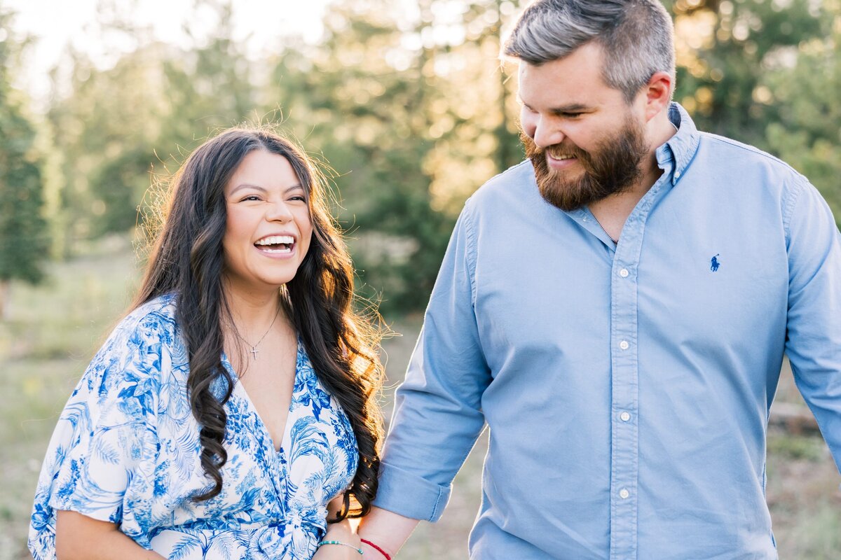 This is a close up shot of a boyfriend and girlfriend. They are each wearing blue and are seen laughing while walking arm in arm. Taken by a local Breckenridge photographer. 