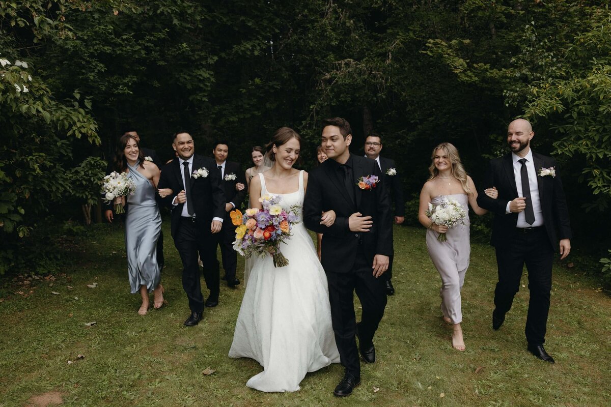 Bridal party walking while holding their flowers designed by the florist Flowers and Thyme.