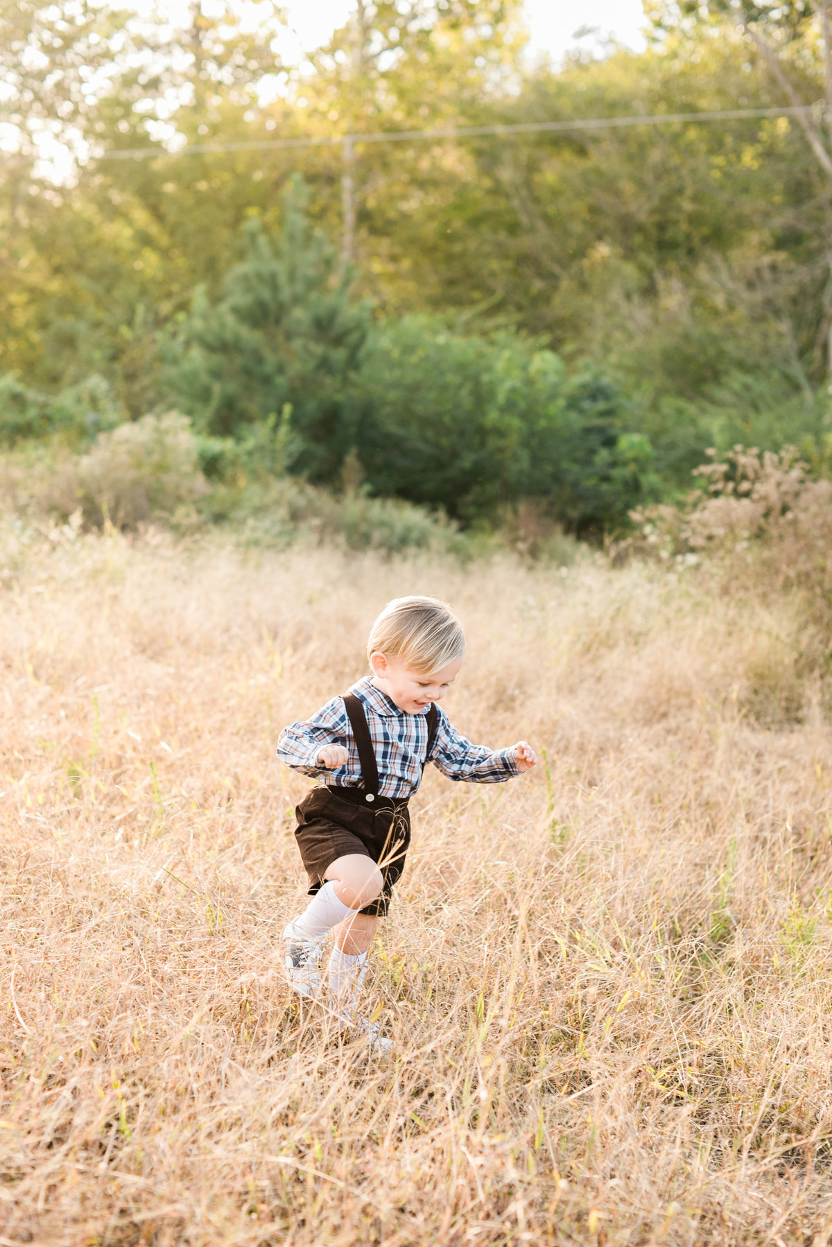 Toddler runs through a field playing during a Raleigh family photo session at Horseshoe Nature Preserve. Photographed by Raleigh NC Family Photographer A.J. Dunlap Photography.