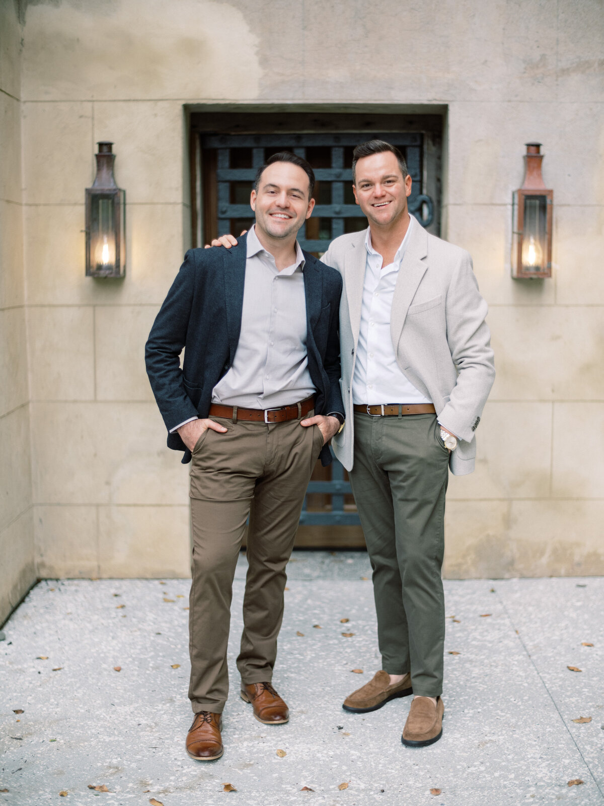 A fashionable couple stands smiling outside, showcasing their smart attire. The relaxed ambiance captures a moment of joy and connection, emphasizing their stylish presence.