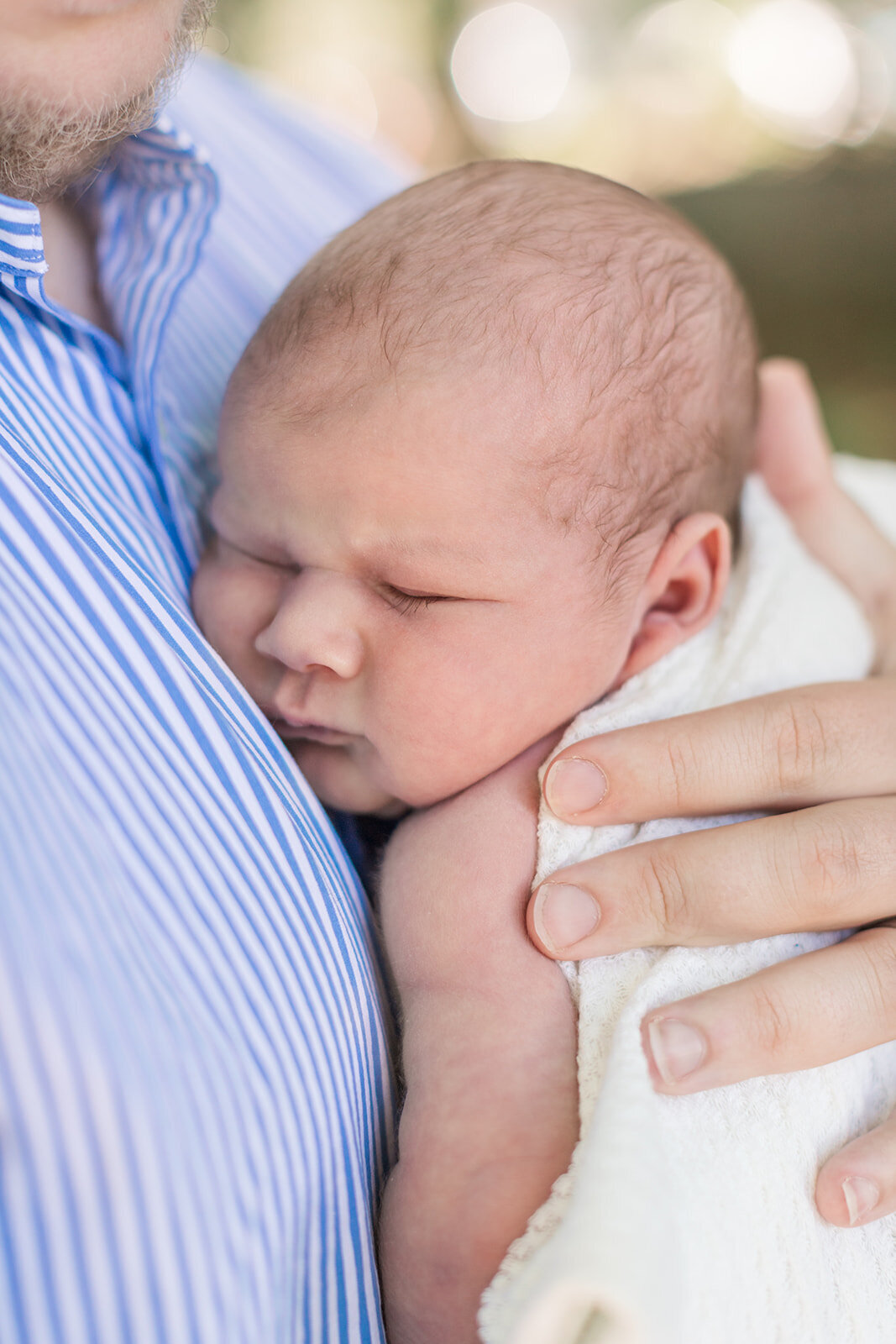 Newborn baby sleeping peacefully in dad's arms