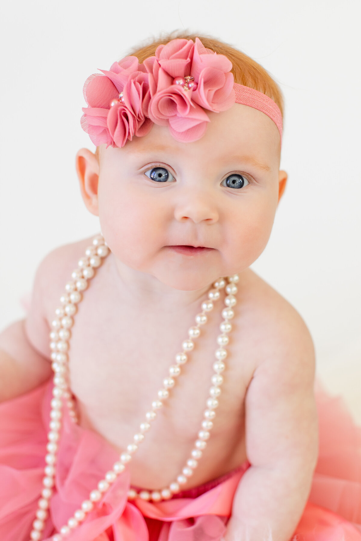 Baby girl in pink tutu and pearls smiling