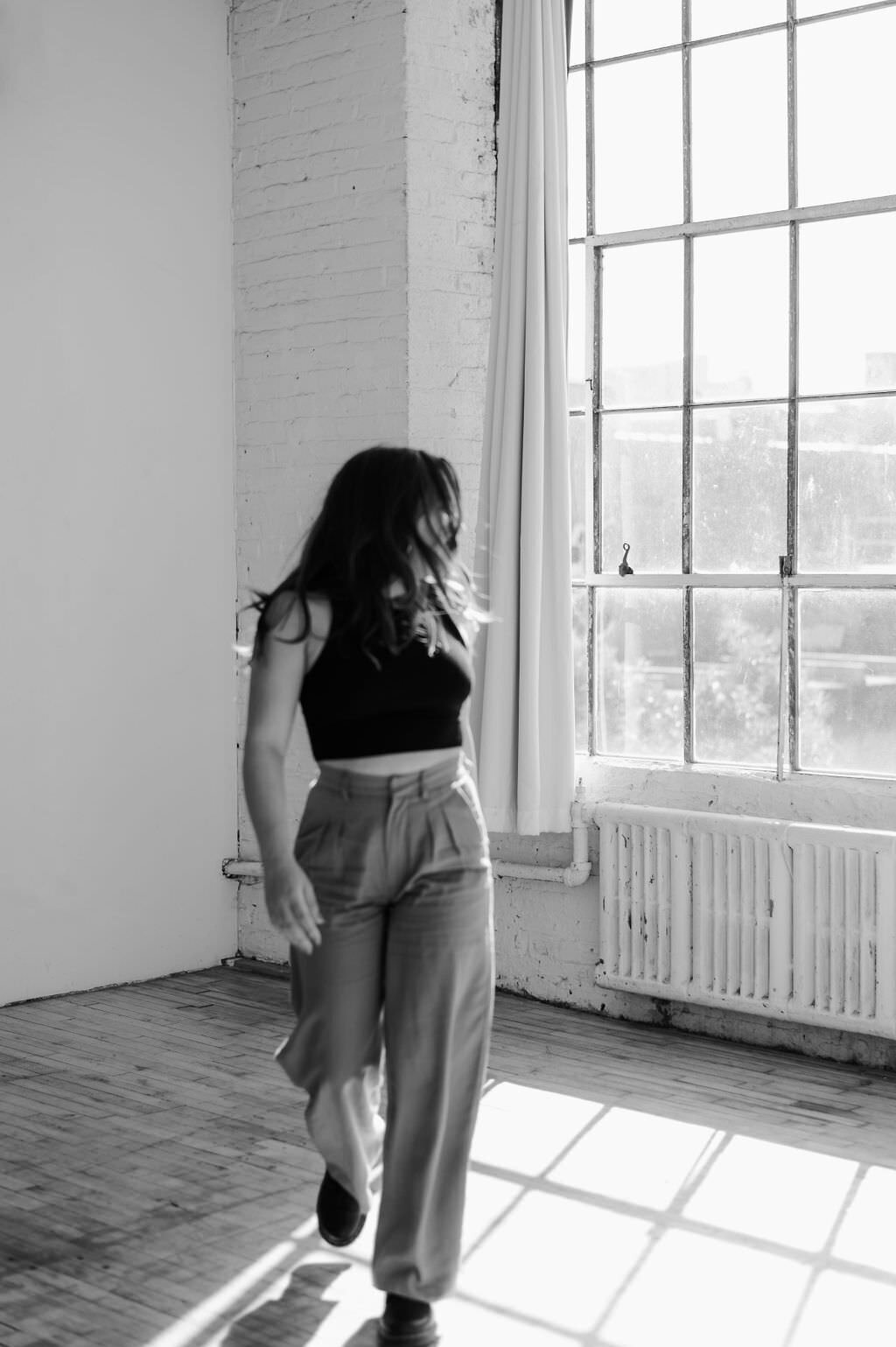 black and white photo of a woman walking in an empty room looking back over her shoulder