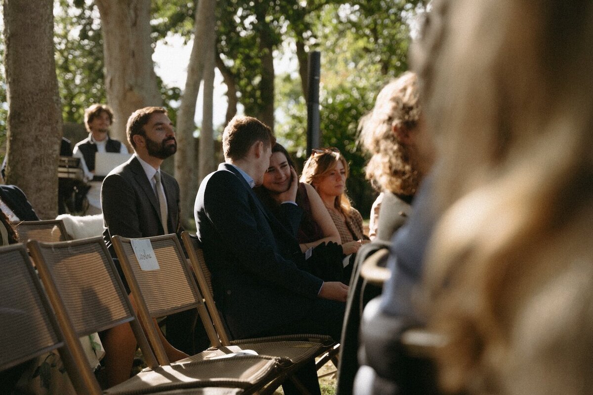 Moment tendre et complice entre un couple entourés d'invités pendant la cérémonie en extérieure au Château de Beaussais. Par Kamescop.