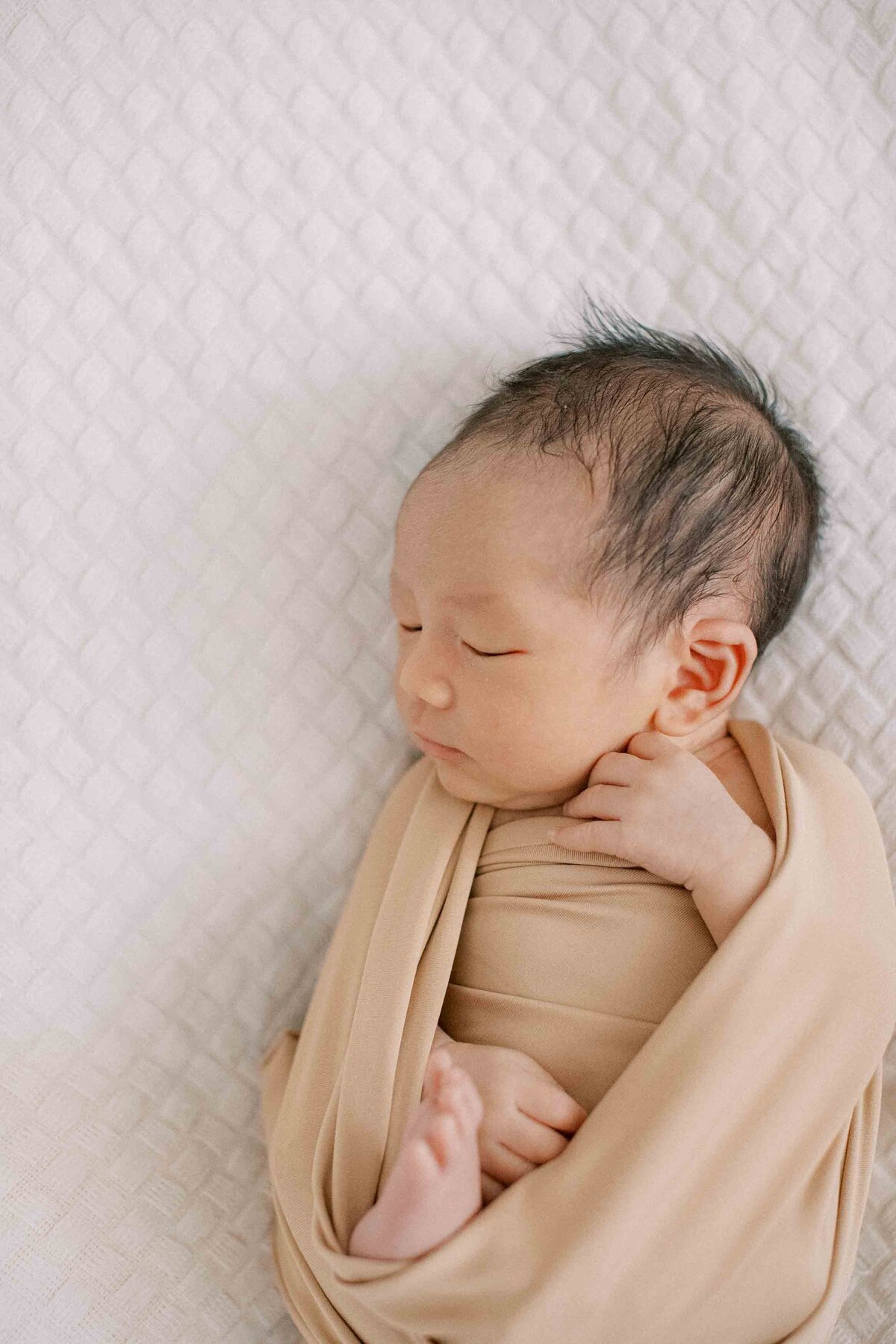 newborn baby boy wrapped in a neutral-colored swaddle