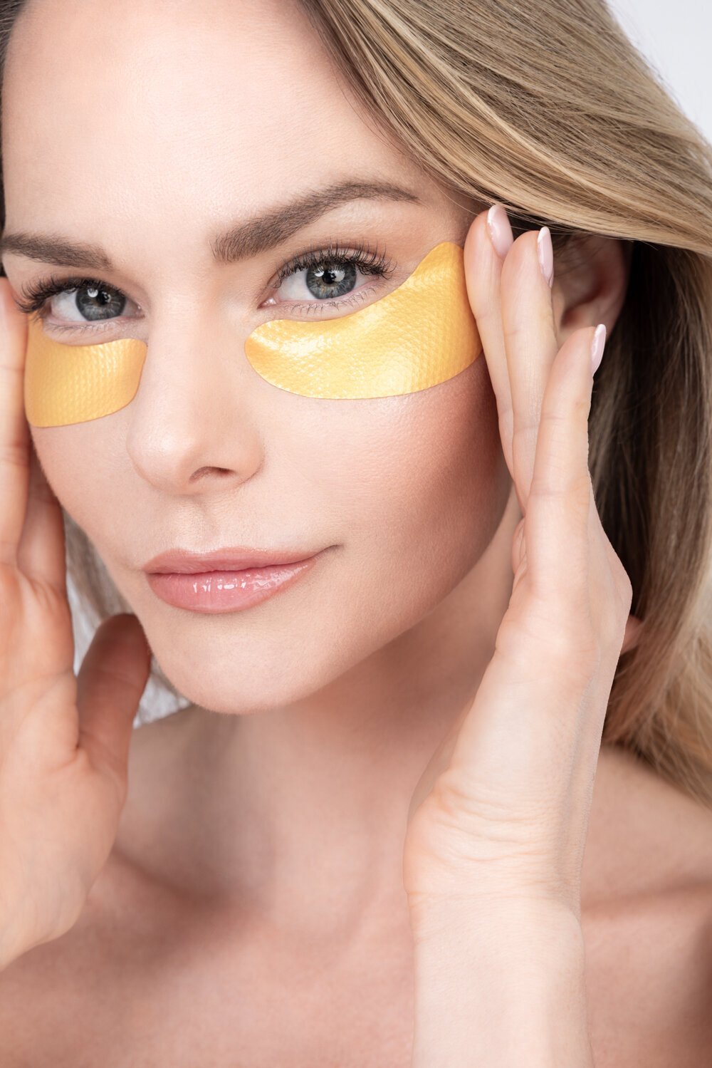 Beauty photography close-up of model applying golden under-eye patches