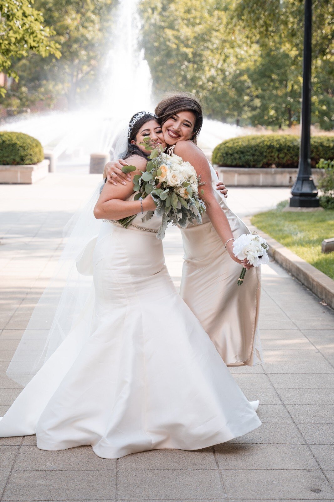 Bride and maid of honor hugging and smiling with bouquets