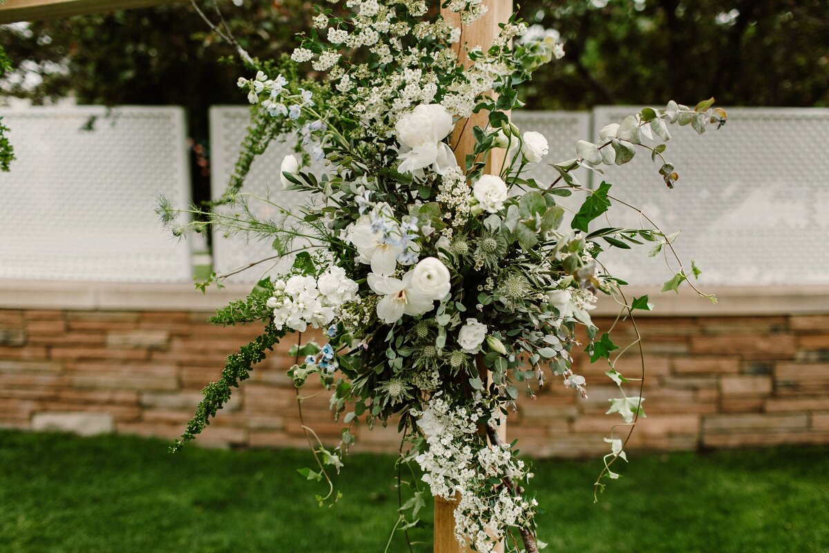 White floral and greenery wedding ceremony arch arrangement.