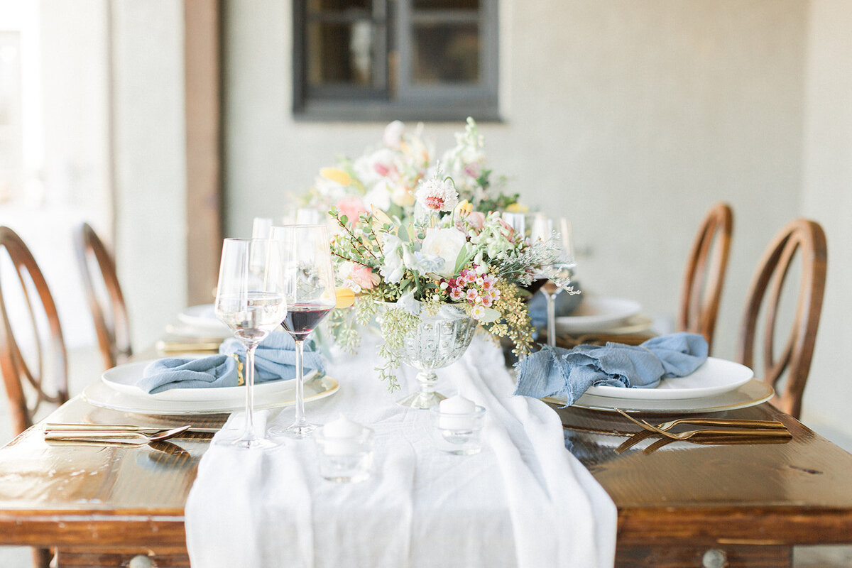 light color tablescape with wine glasses and blue napkins
