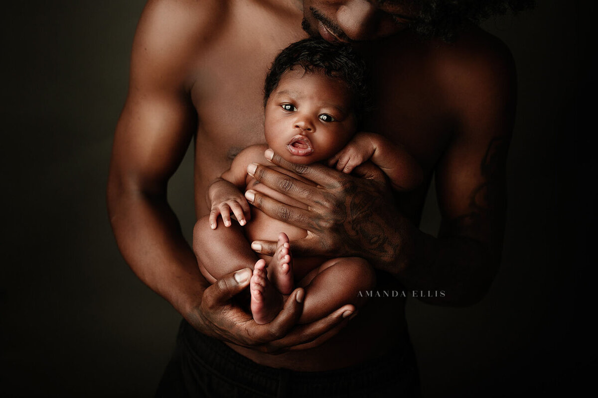 Dark and moody portrait of father with newborn