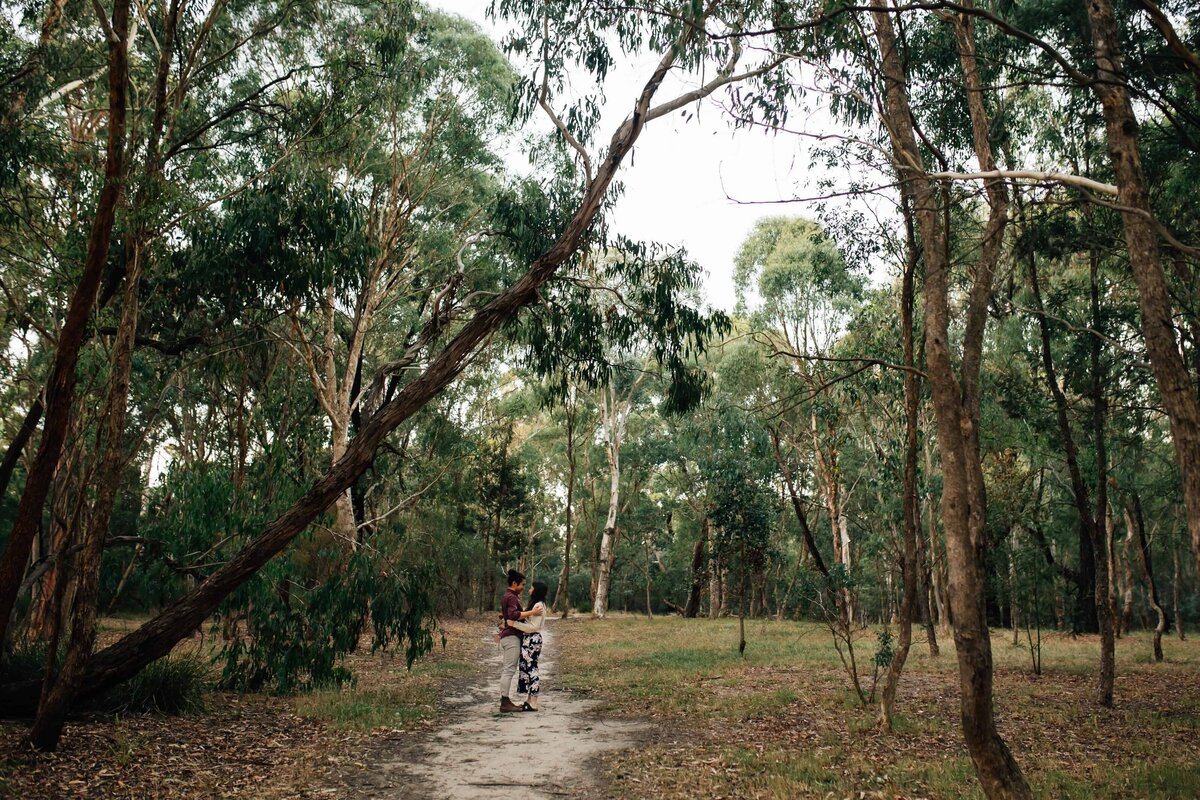 Couple embracing in distance in bushland during proposal photoshoot Melbourne