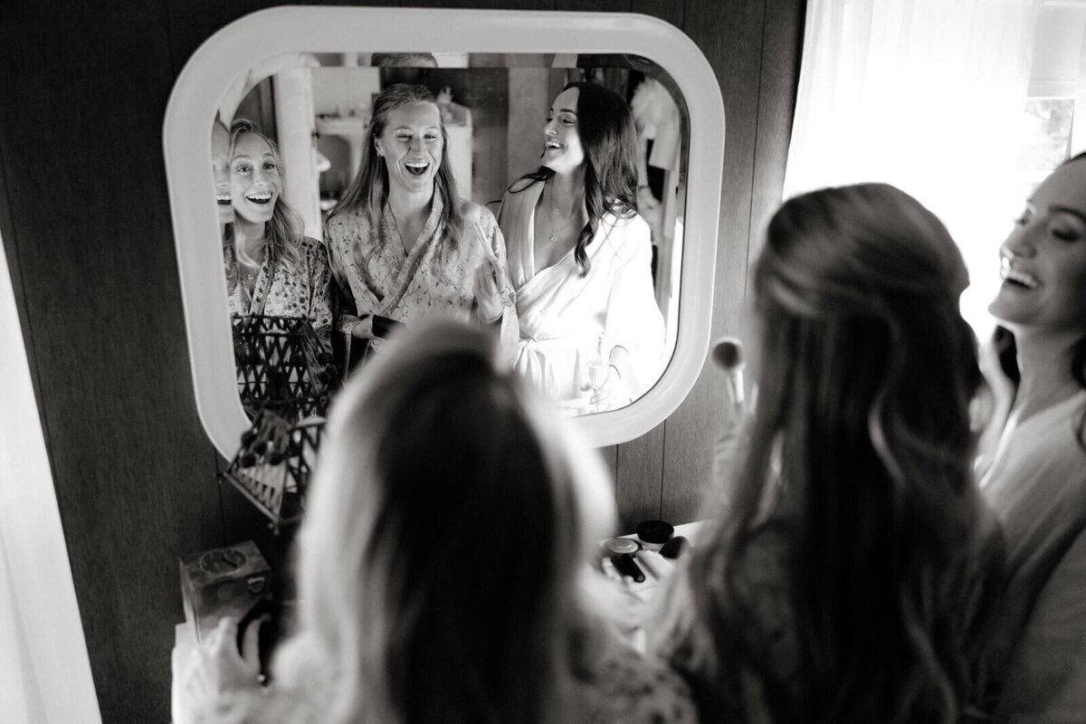 The bride and two other women are doing their make-up in a room at The Ausable Club, New York.