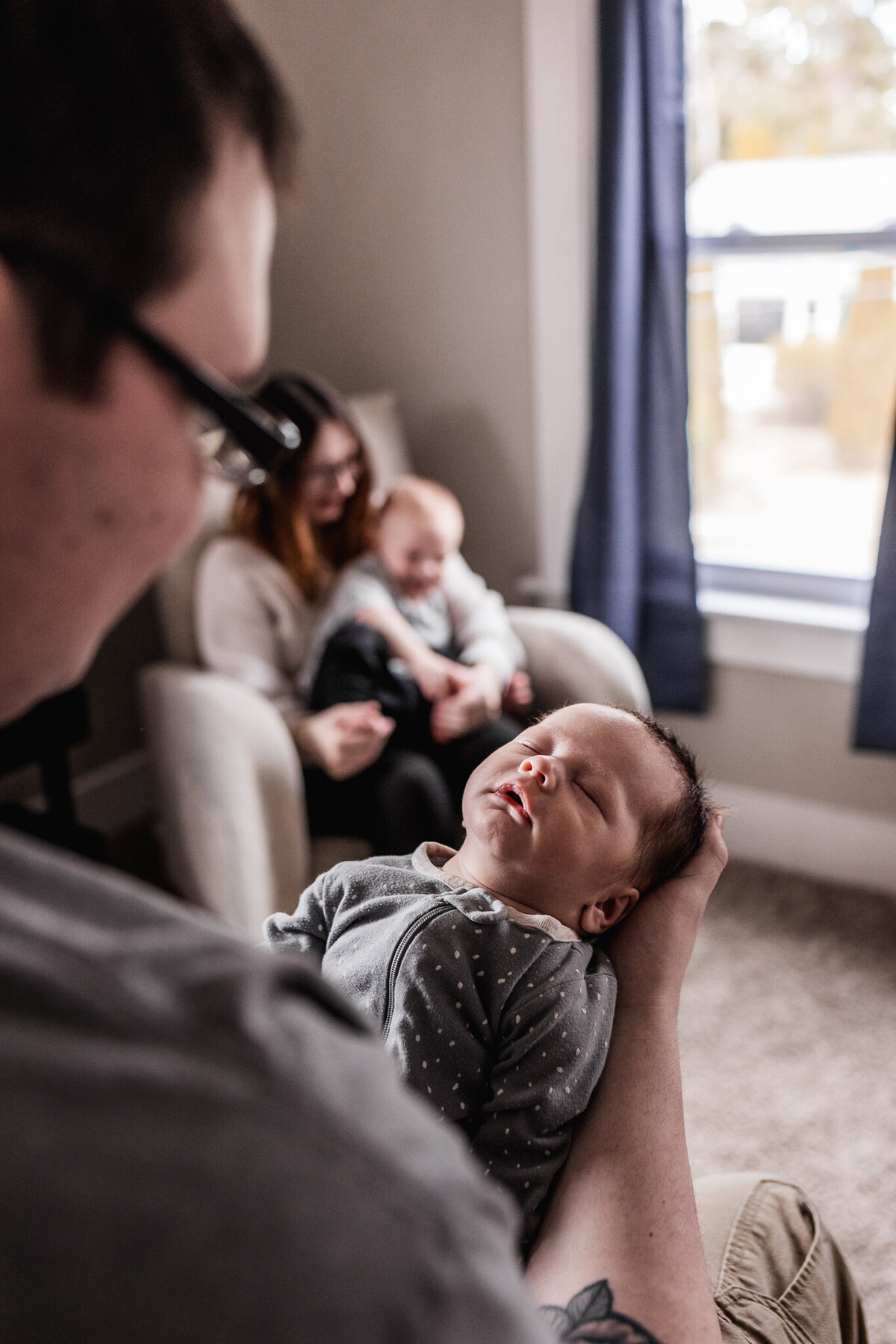 In home newborn session with dad holding baby and mom holding older brother by lisa smith photography