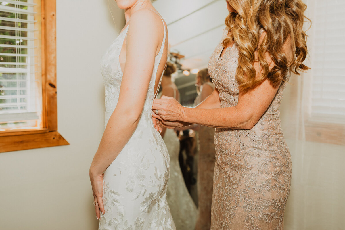 Mother Buttoning up her Daughter's Wedding Dress