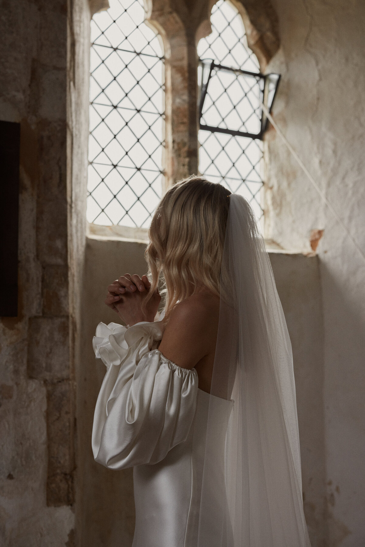Bride looking out of window in silk wedding dress, handmade bridal gown with detachable sleeves by Luna Bea
