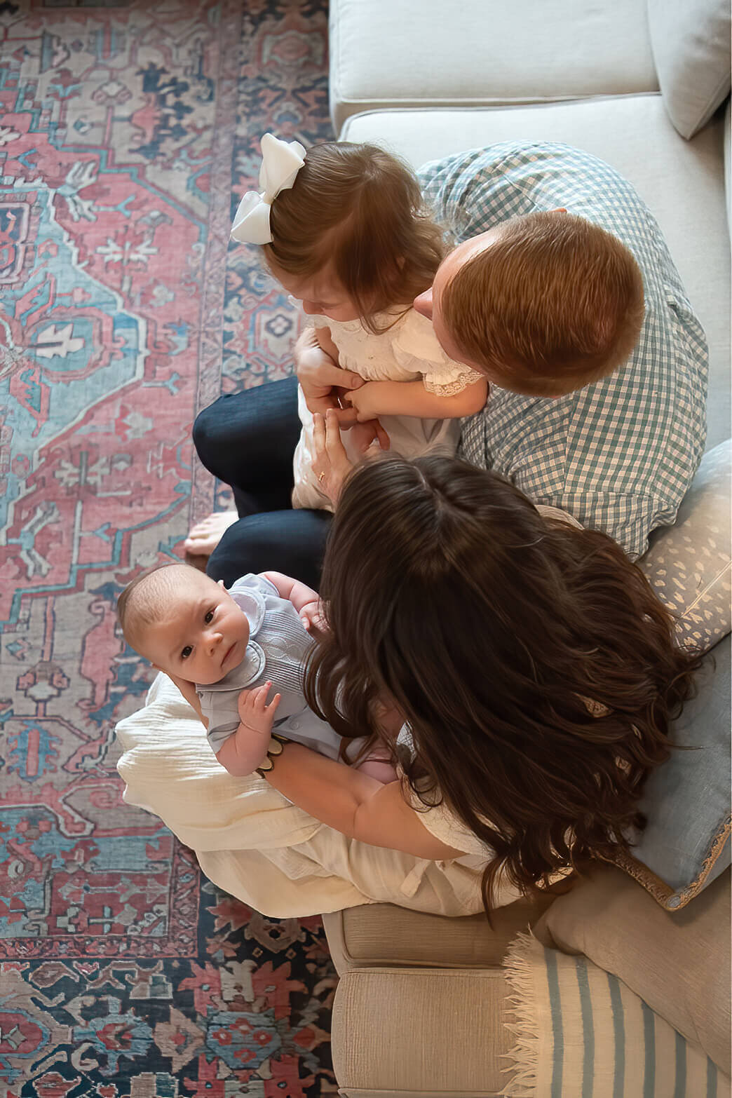 A young family looks down at their newborn, while the baby looks up at the camera.