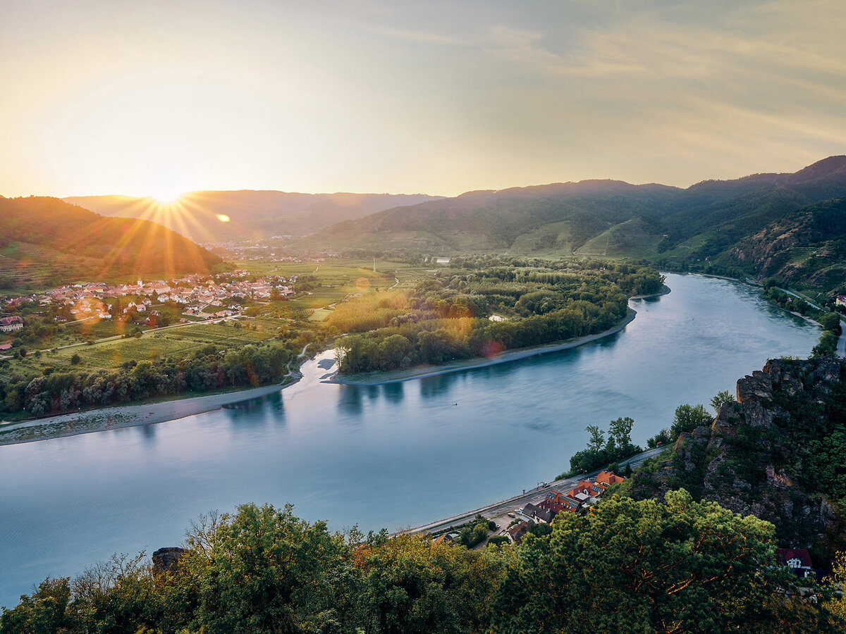 Die Donau im warmen Abendlicht mit Blick auf Dürnstein und die umliegenden Weinberge – stimmungsvolle Landschaftsaufnahme aus der Wachau