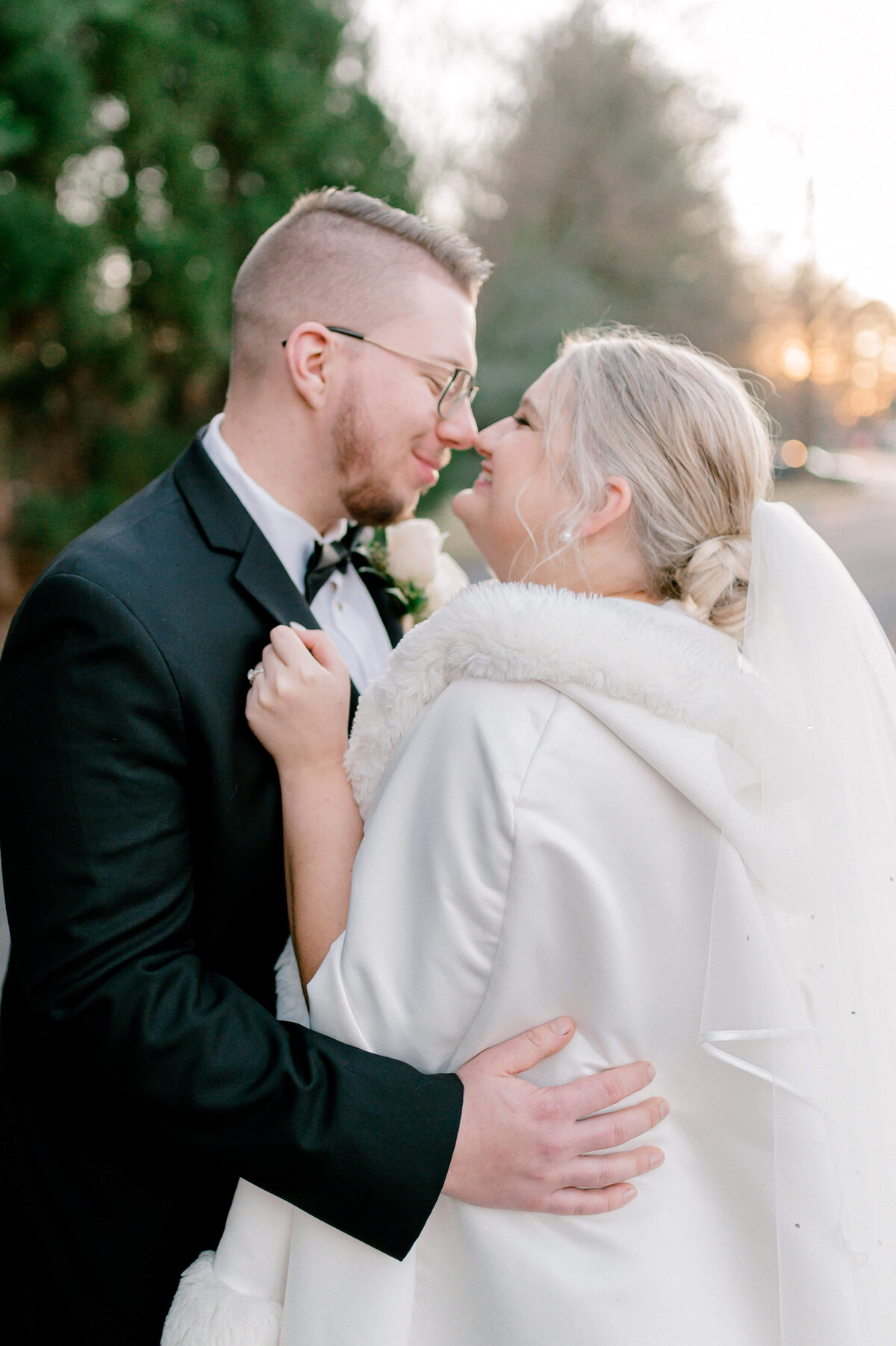 Romantic portrait of bride and groom snuggling close during winter portraits