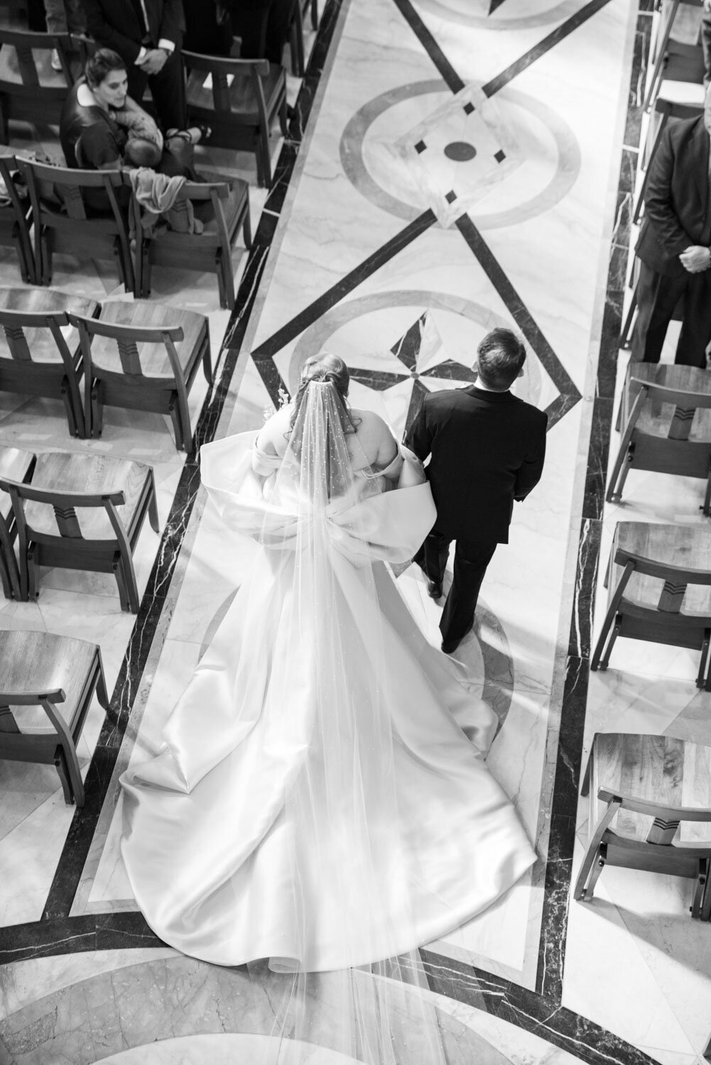 A black and white photo of a bride and groom walking down the aisle