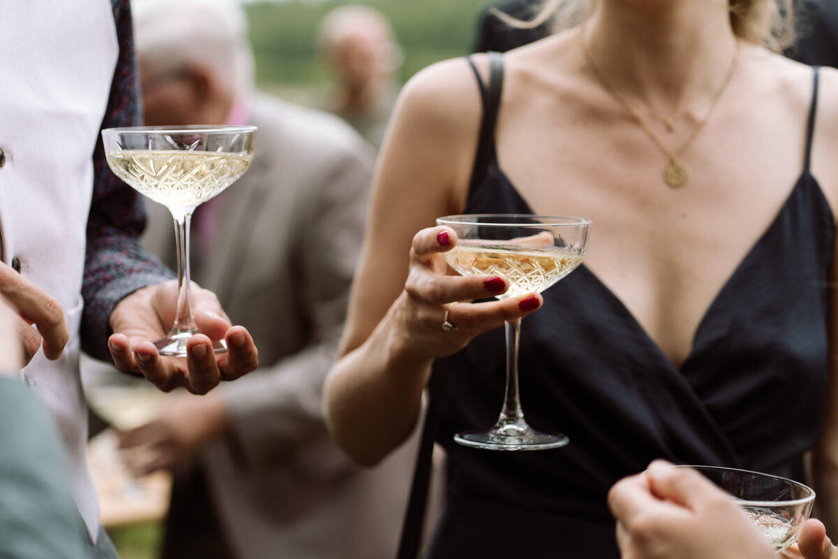 Bruiloft sfeerbeeld van de borrel. Je ziet gasten champagne drinken. 
