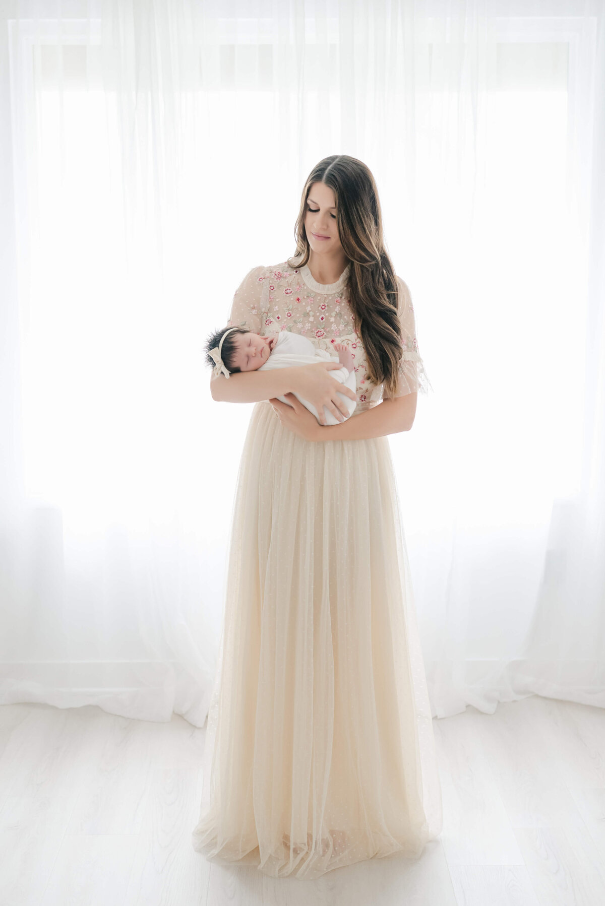 gorgeous mom wearing needle and thread dress with newborn baby girl