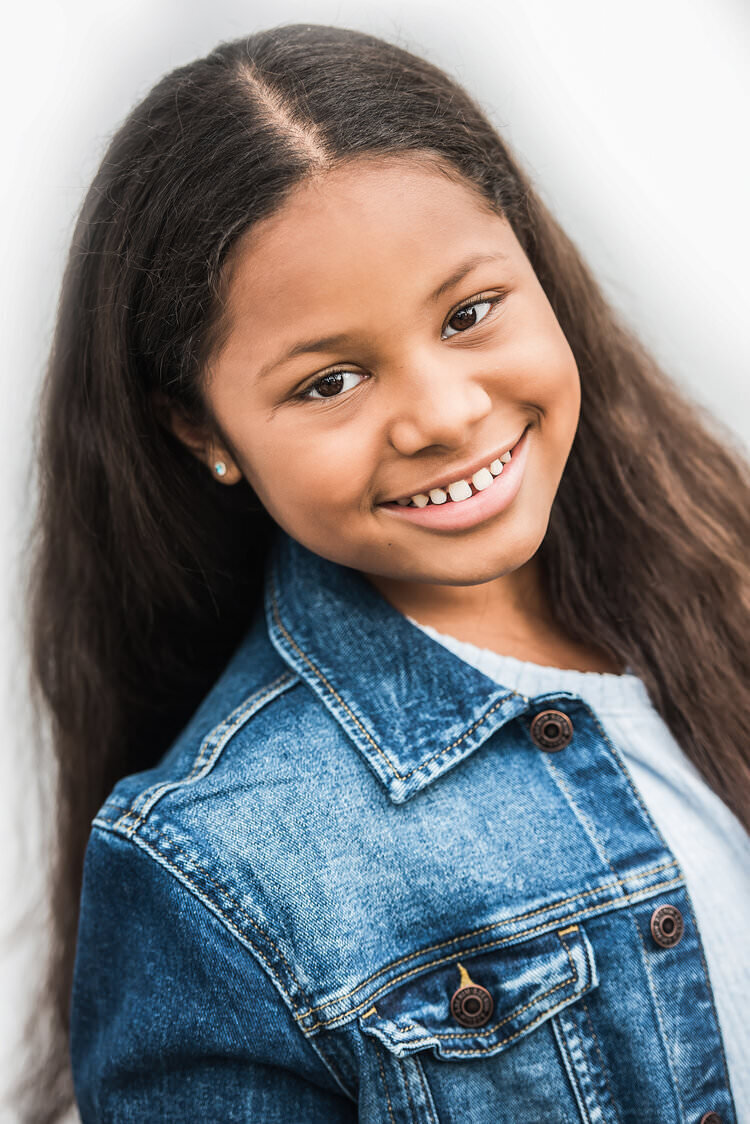 A small girl smiling in a jean jacket