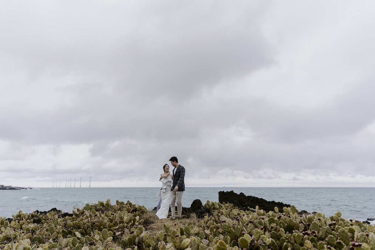 the couple standing at the cactus coastline in jeju island